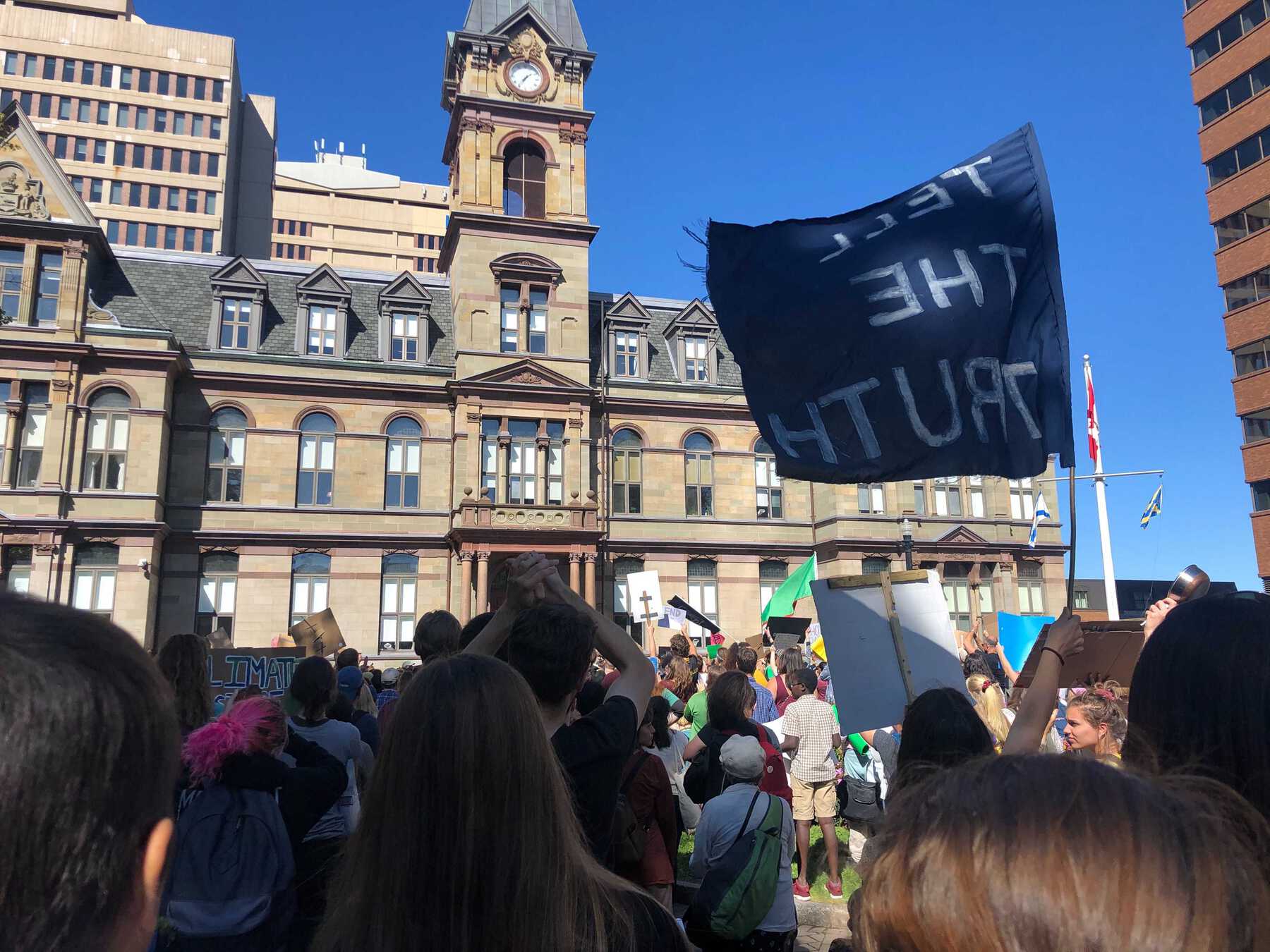 Crowd with sign reading 'TELL THE TRUTH' in front of government building