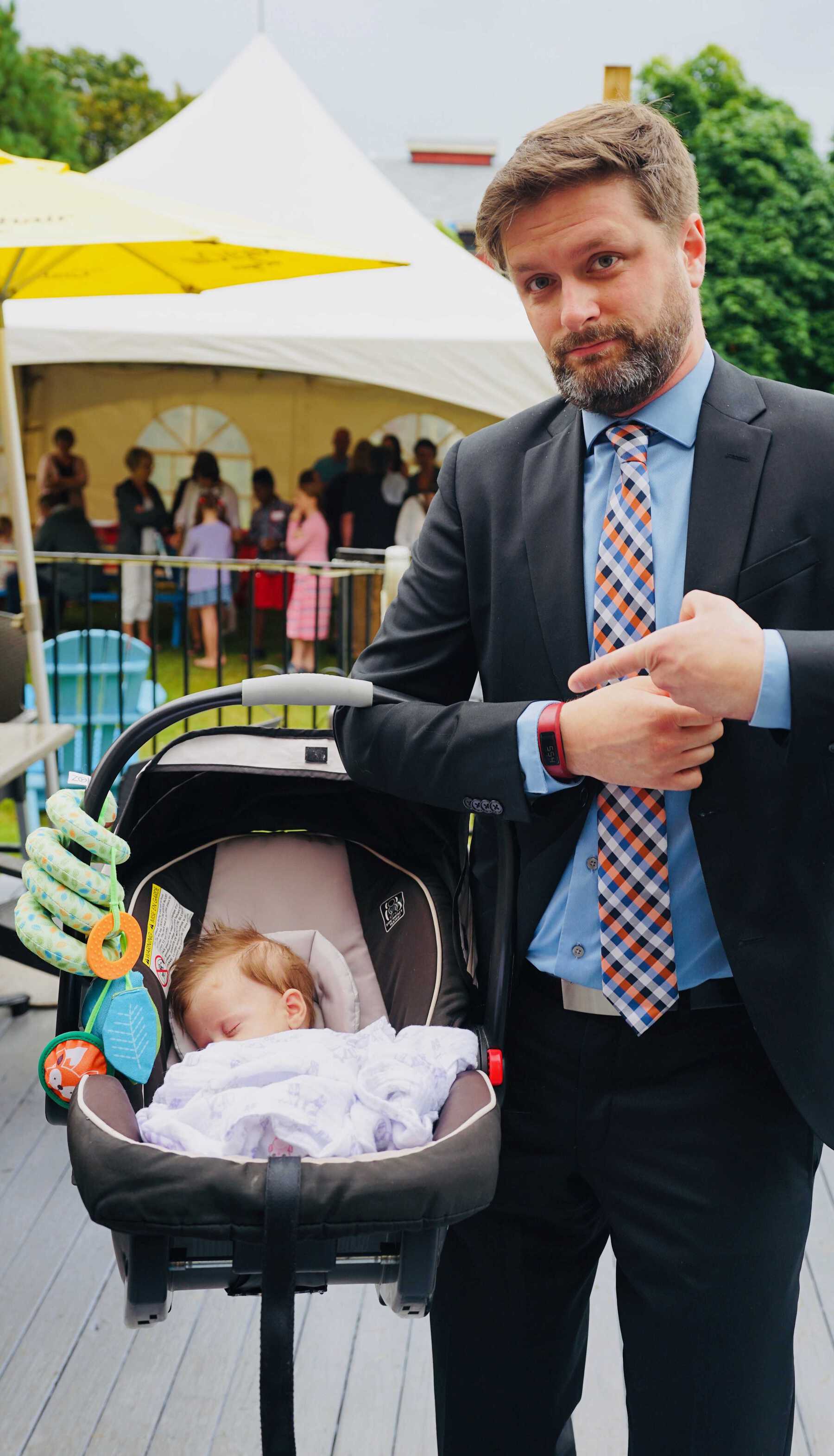 Man in suit holding baby in car seat