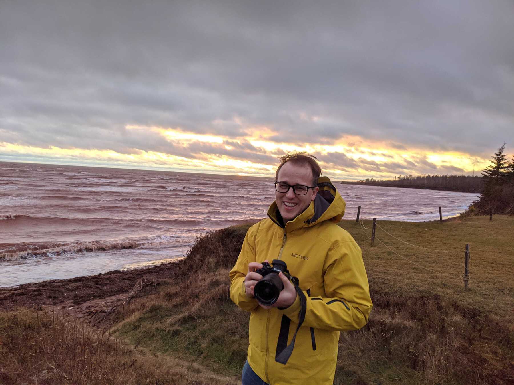 Man with camera and raincoat on shore