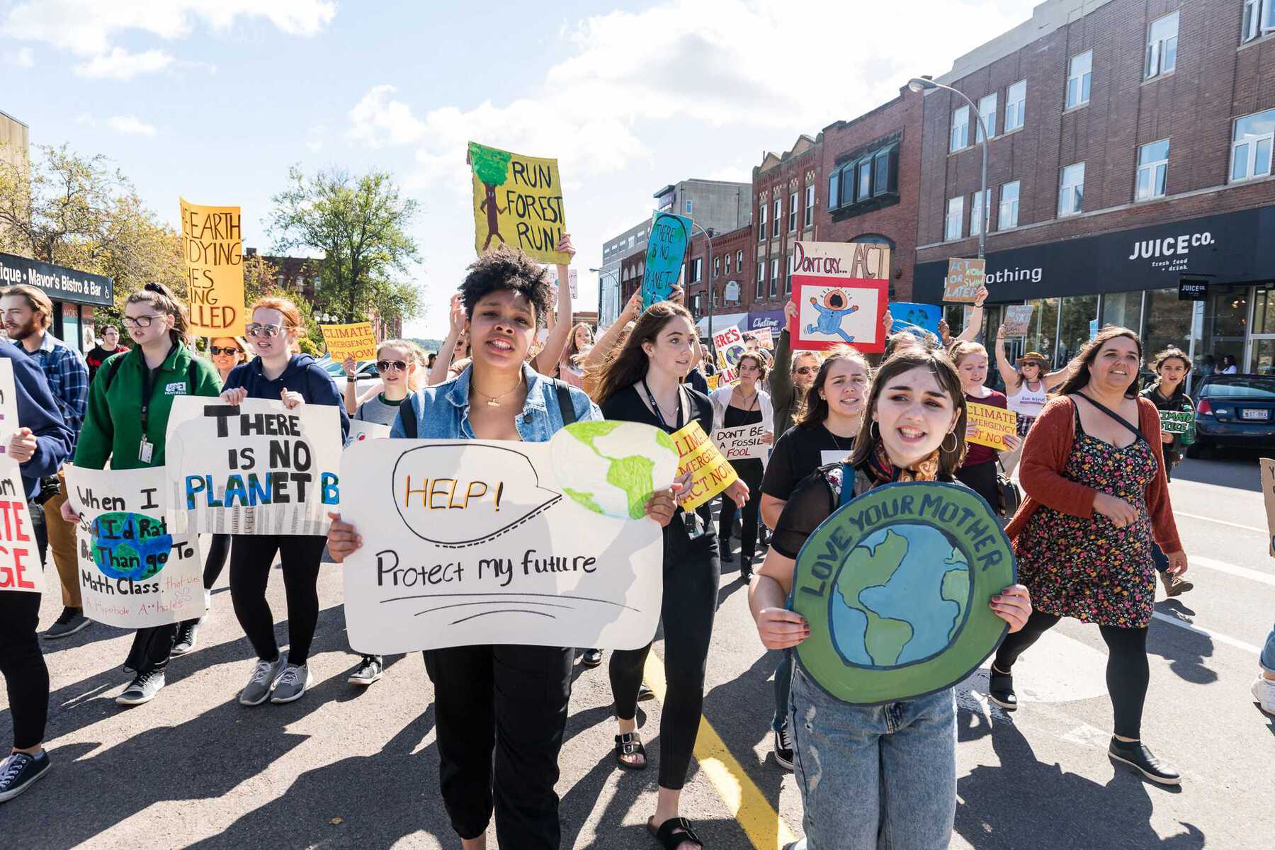 Crowd of young protesters marching with signs reading 'Help protect my future'