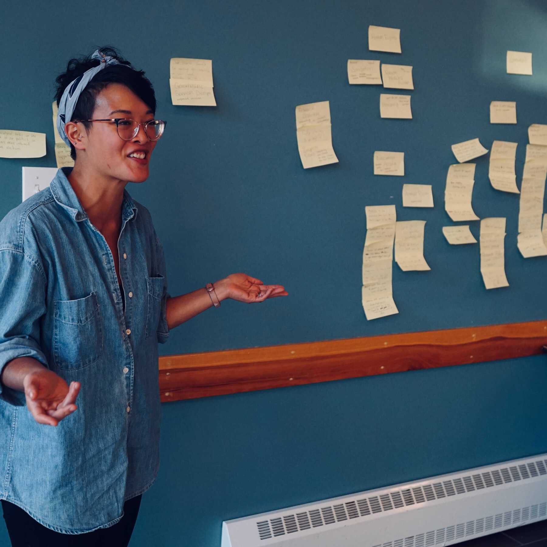 Woman smiling in front of wall with post-it notes